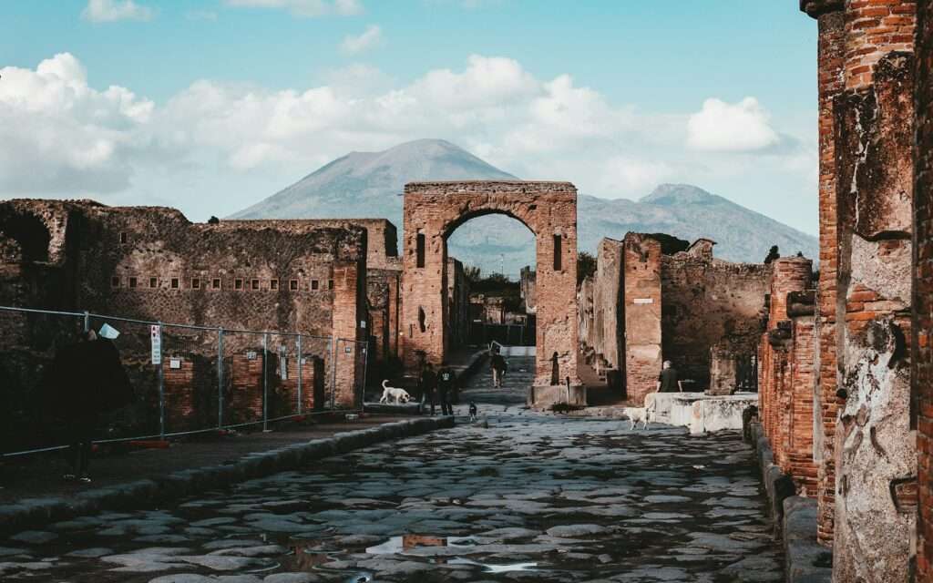 A Pompeii street and brick arch with Vesuvius rising behind